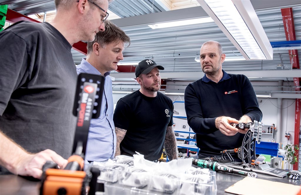 Asetek’s CEO André Eriksen og Henrik Gertz, VP Global Operations, (de to på foto 1 – André med logo på mørkeblå trøje) glæder sig - sammen med medarbejdere i den nye afdeling - over, at produktionen af de første SimSports produkter nu er godt i gang – og allerede overstrømmende bedømt af internationalt anerkendte anmeldere.
(Foto: Asetek SimSports / René Schütze)
